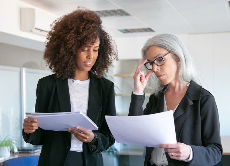 Dos consultoras senior de Cohen & Aguirre realizando una auditoría de Due Diligence y revisando documentos financieros para la compra de un negocio en España.