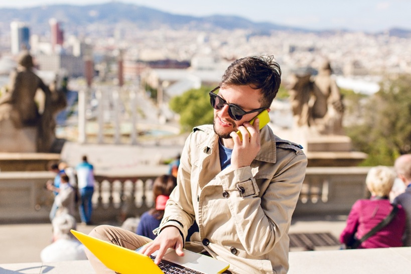 Emprendedor extranjero con portátil y móvil en Barcelona, clave para emprender en España 2025.